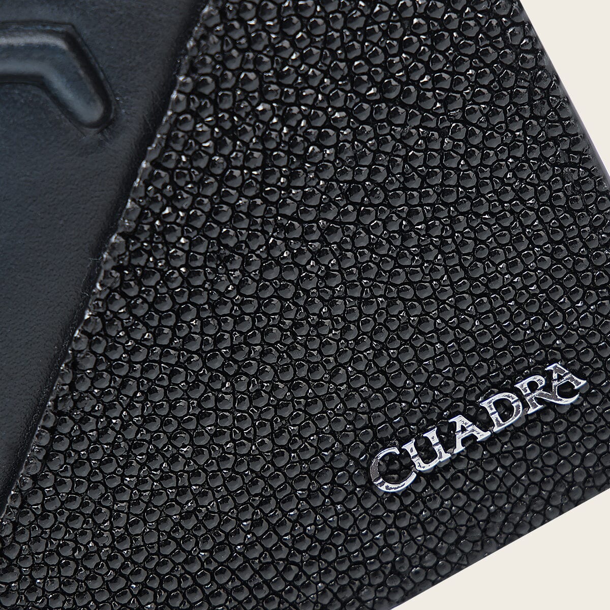 Close-up of the stingray leather and metal Cuadra logo on the DU717 wallet